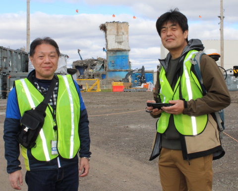 Two men in yellow safety vests smile for a picture