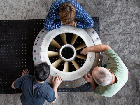 Three workers examining a hydropower turbine
