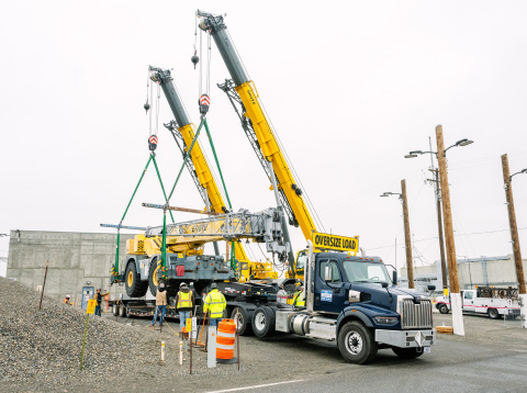 A large yellow crane lifting a piece of equipment with workers around it