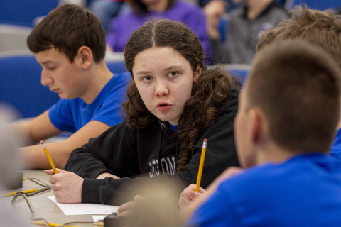 Middle school students sitting at a table participating in a science bowl