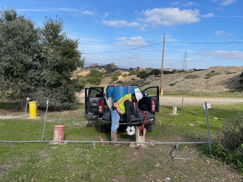 An employee outside taking measurements of groundwater at the ETEC site