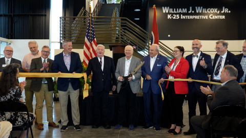 A group of individuals cutting a large ribbon to signify the opening of a Center