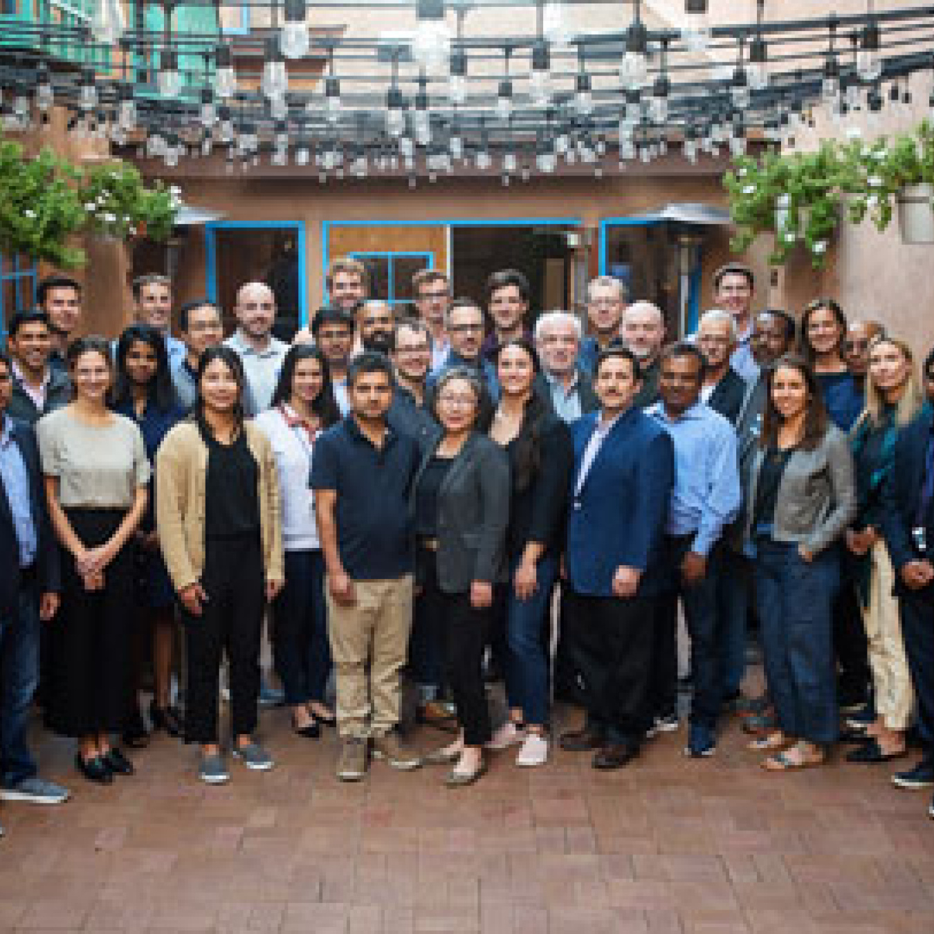 Men and women stand together for a group photo on an enclosed outdoor patio.