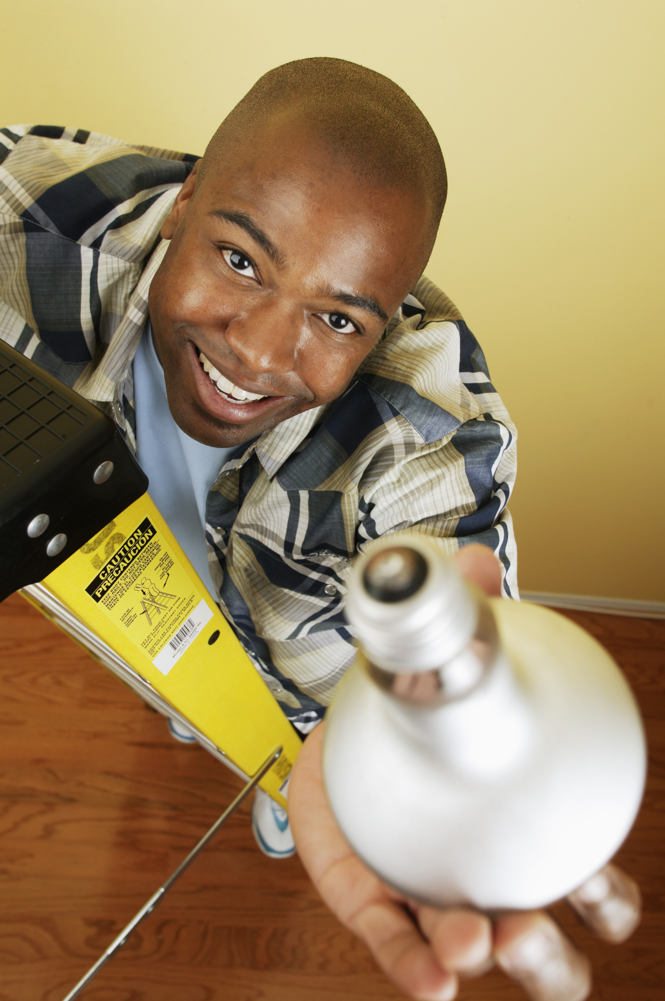 A young man holds a lightbulb up in the air.