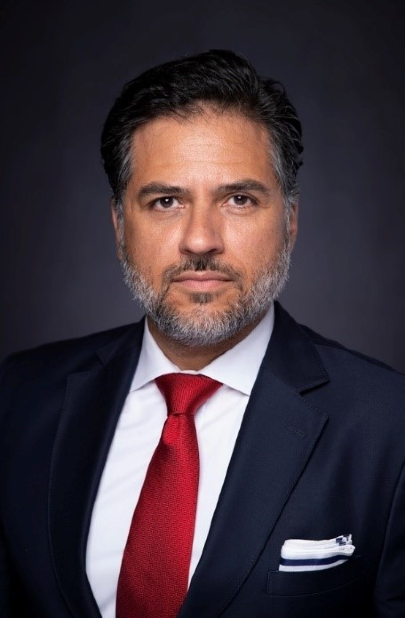 A picture of Deputy Assistant Secretary Josh Volz in a suit and red tie.