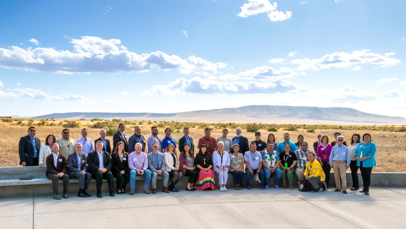 A large group photo taken outside with mountains in the background.