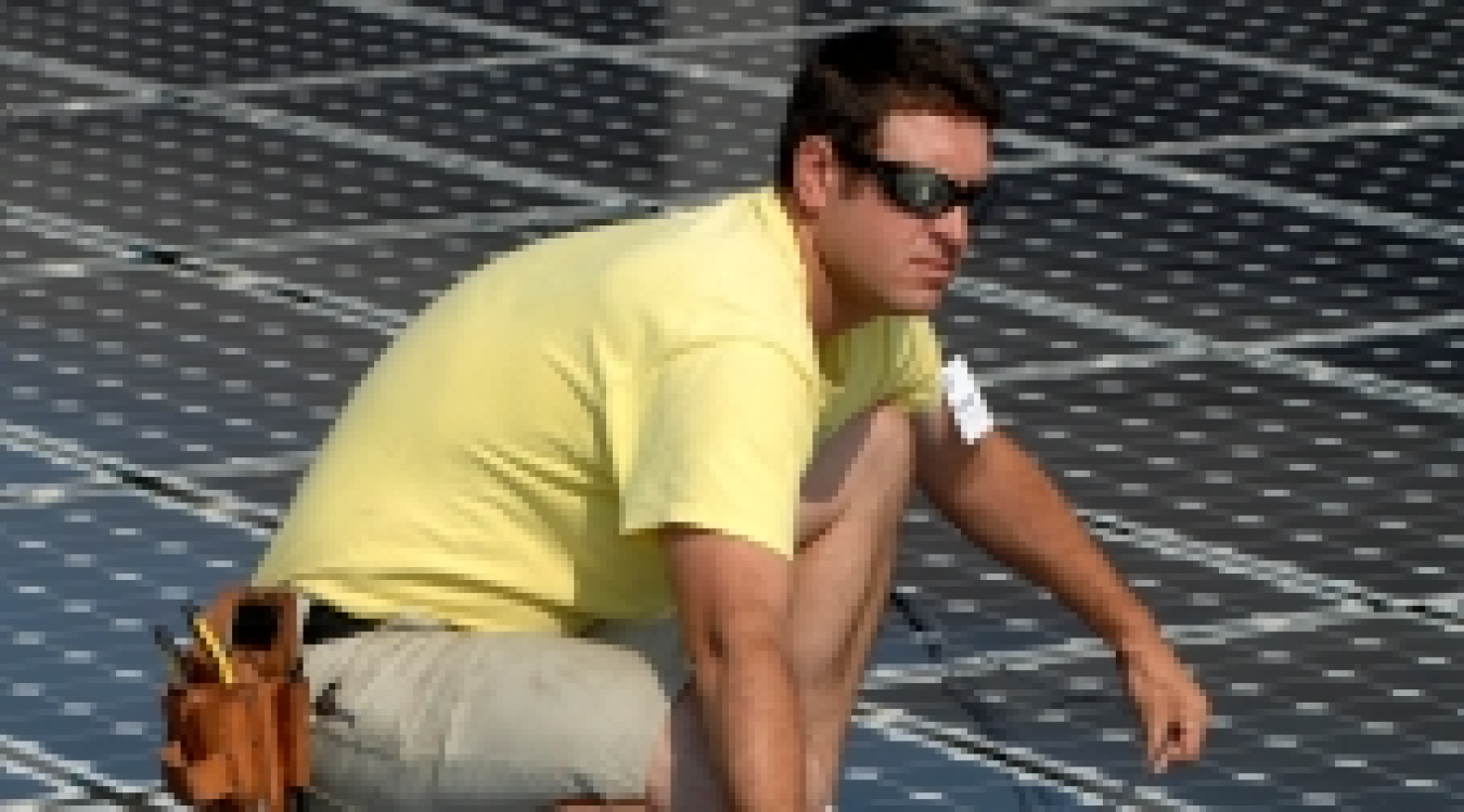 Photo of a young man working on solar panels.