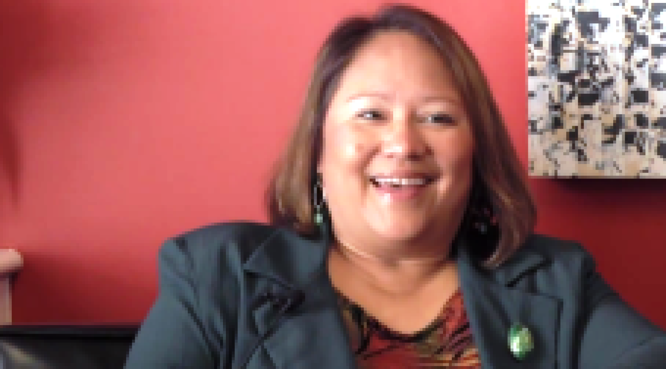 Photo of a woman laughing, looking at the camera.