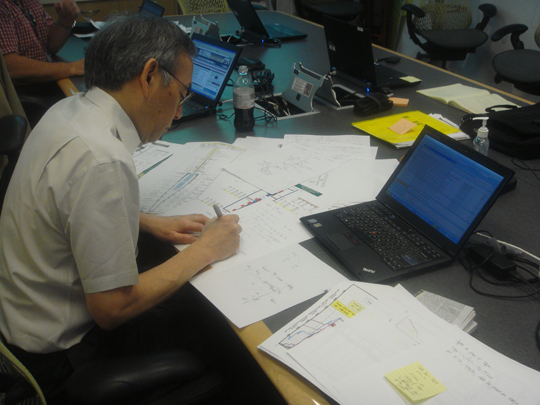 Secretary Steven Chu works on flow and resistance calculations on a conference room table