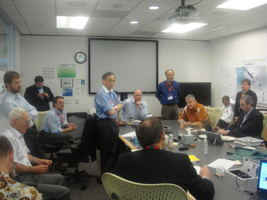 Secretary Steven Chu and National Laboratory scientists review options over a conference room table.
