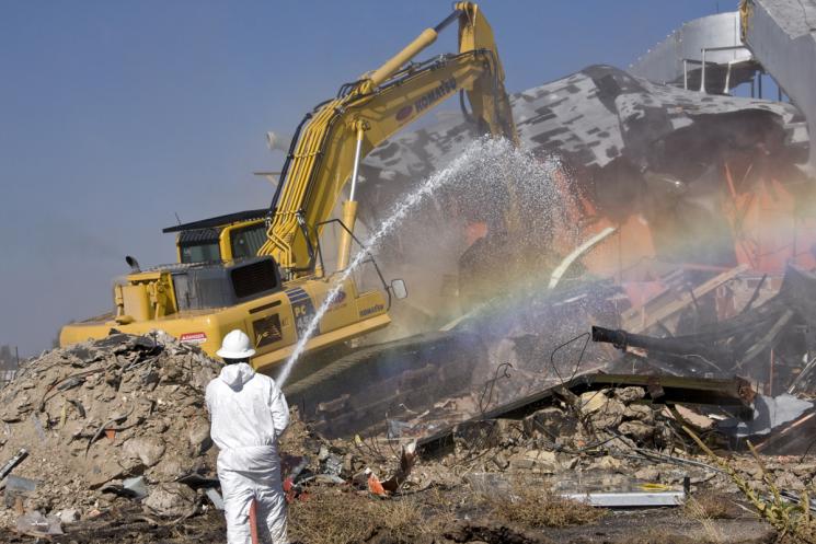 A worker suppresses dust during the final demolition stages of the historic DP West site, located at Los Alamos National Laboratory’s (LANL) Technical Area 21. The demolition was funded by the American Recovery and Reinvestment Act (ARRA) and is part of $212 million in ARRA funds the Lab received for environmental remediation. | Photo courtesy of Los Alamos National Laboratory.