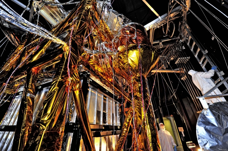 The James Webb Space Telescope is a large, infrared-optimized telescope that is anticipated to launch in 2018. The spider-like sheets and tubes of wires you see here are the Optical Telescope Simulator (OSIM) for the telescope itself. OSIM will help scientists prepare the Webb telescope for flight by generating a beam of light that the telescope optics will feed into its actual flight instruments.
In this photo, engineers have blanketed the OSIM with special insulating material to help control its temperature while it goes into the deep freeze testing of the Space Environment Simulator at NASA's Goddard Space Flight Center in Greenbelt, Maryland. The simulator will mimic the environment that the telescope will experience in operational orbit, more than 1 million miles from Earth. | Photo credit: Chris Gunn/NASA. The James Webb Space Telescope is a large, infrared-optimized telescope that is anticipated to launch in 2018. The spider-like sheets and tubes of wires you see here are the Optical Telescope Simulator (OSIM) for the telescope itself. OSIM will help scientists prepare the Webb telescope for flight by generating a beam of light that the telescope optics will feed into its actual flight instruments.
In this photo, engineers have blanketed the OSIM with special insulating material to help control its temperature while it goes into the deep freeze testing of the Space Environment Simulator at NASA's Goddard Space Flight Center in Greenbelt, Maryland. The simulator will mimic the environment that the telescope will experience in operational orbit, more than 1 million miles from Earth. | Photo credit: Chris Gunn/NASA.