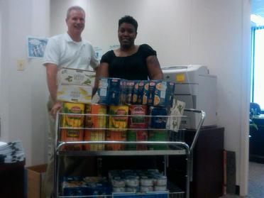 Barry Gaffney and Evette Dillon with EM's Office of Program Planning and Budget stand behind a portion of the office's donations to Feds Feed Families. Barry Gaffney and Evette Dillon with EM's Office of Program Planning and Budget stand behind a portion of the office's donations to Feds Feed Families.