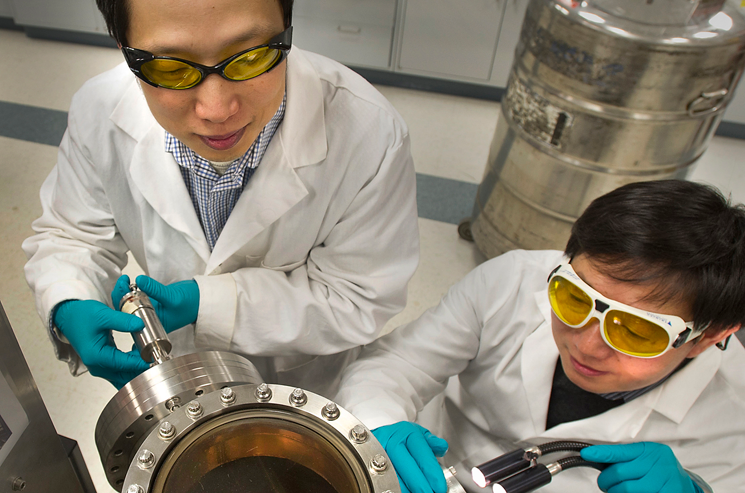 Brookhaven physicists Weidong Si (left) and Qiang Li look into the vacuum chamber where the new high-field iron-based superconductors are made through a process called pulsed-laser deposition. Brookhaven physicists Weidong Si (left) and Qiang Li look into the vacuum chamber where the new high-field iron-based superconductors are made through a process called pulsed-laser deposition.