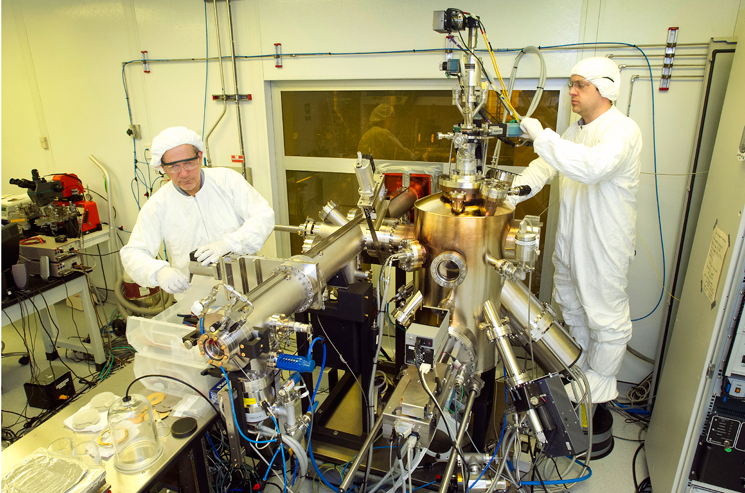 Inside a clean room, Brookhaven physicists Ivan Bozovic (left) and Anthony Bollinger work on the molecular beam epitaxy system that produced the atomically perfect materials used in the study. | Photo courtesy of Brookhaven National Lab Inside a clean room, Brookhaven physicists Ivan Bozovic (left) and Anthony Bollinger work on the molecular beam epitaxy system that produced the atomically perfect materials used in the study. | Photo courtesy of Brookhaven National Lab