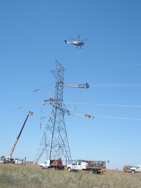 A helicopter hoists platforms for linemen during the construction of this single-circuit 500-kilovolt tower – one of hundreds on the McNary-John Day line saving BPA big bucks. | Photo courtesy of Bonneville Power Administration A helicopter hoists platforms for linemen during the construction of this single-circuit 500-kilovolt tower – one of hundreds on the McNary-John Day line saving BPA big bucks. | Photo courtesy of Bonneville Power Administration