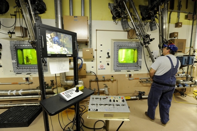 An operator uses robotic manipulators to process RH TRU. An operator uses robotic manipulators to process RH TRU.