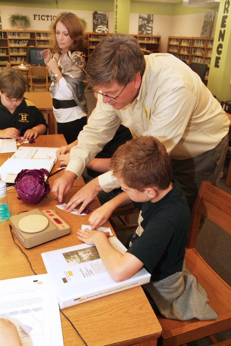 Mentor Jim Erickson of the LATA Kentucky team shows Heath Middle School sixthgrader Ian Morgan how to use red cabbage to indicate if a watery solution is acidic, basic, or neutral.