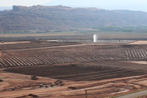 Pictured here is the Moab uranium mill tailings pile. Tailings excavation and conditioning activities are seen in the foreground. The water spray is used to eliminate extracted contaminated groundwater. Pictured here is the Moab uranium mill tailings pile. Tailings excavation and conditioning activities are seen in the foreground. The water spray is used to eliminate extracted contaminated groundwater.