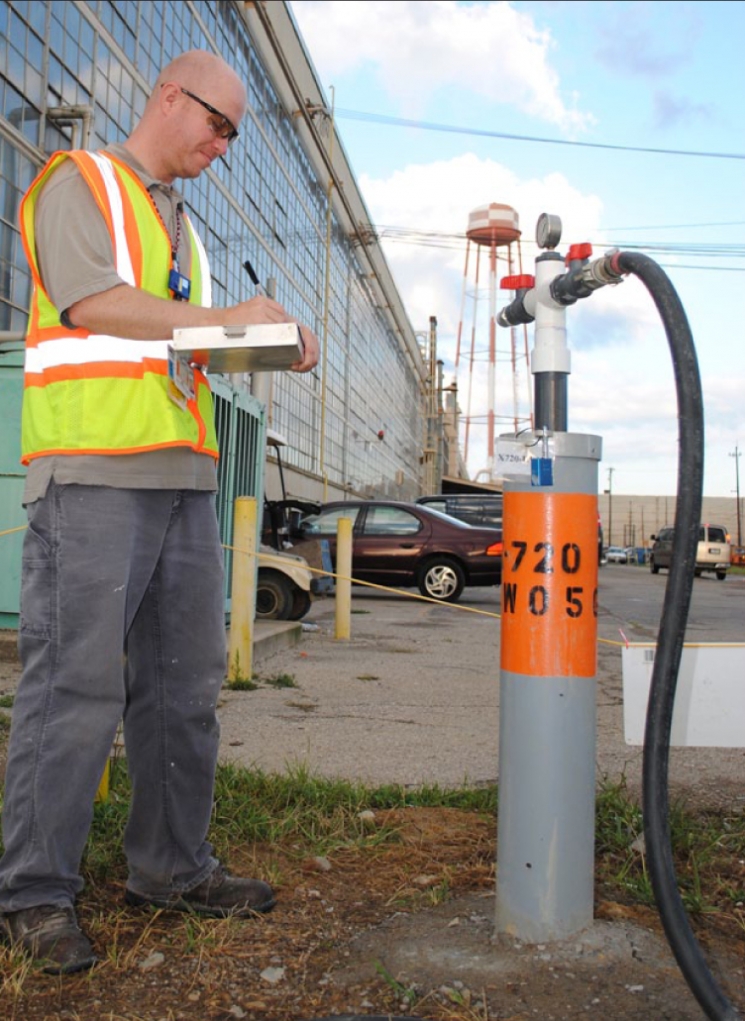 Neil Smith puts a trained eye on the pressure and flow of a food-grade com¬pound being injected into an under¬ground plume of hazardous waste near the X-720 Maintenance Facility at the DOE Piketon Site. The sodium lactate compound promotes bacterial growth in the groundwater that turns hazardous waste into harmless end-products. Neil Smith puts a trained eye on the pressure and flow of a food-grade com¬pound being injected into an under¬ground plume of hazardous waste near the X-720 Maintenance Facility at the DOE Piketon Site. The sodium lactate compound promotes bacterial growth in the groundwater that turns hazardous waste into harmless end-products.