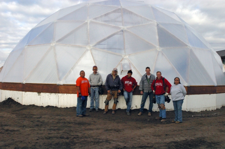 Tribal construction workers stand in front of the hexagonal greenhouse dome structure that will house the seeds for revegetation efforts. Tribal construction workers stand in front of the hexagonal greenhouse dome structure that will house the seeds for revegetation efforts.