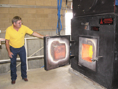 Darby Schools received a woodchip heating system in 2003. Rick Scheele, facilities manager for the Darby schools, shows off the wood firebox | Photo Courtesy USFS Fuels for Schools, Dave Atkins Darby Schools received a woodchip heating system in 2003. Rick Scheele, facilities manager for the Darby schools, shows off the wood firebox | Photo Courtesy USFS Fuels for Schools, Dave Atkins