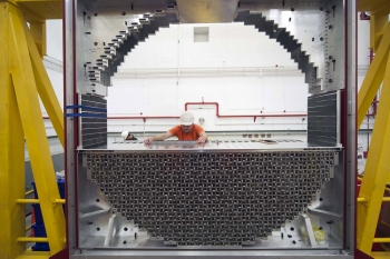 On June 6, 2013, researchers at Jefferson Lab completed the construction of the Forward Calorimeter in Hall D. The calorimeter was built to measure the energy of particles as they are created inside the target area and strike against lead glass blocks that make up the calorimeter. Upon striking the calorimeter, the particles will create a shower of light, which will then be digitized and used to measure energy of particles.
In this photo, John Leckey, a postdoctoral researcher from Indiana University, is assembling the Forward Calorimeter in Jefferson Lab's newest experimental area, Hall D. Leckey helped assemble the calorimeter along with Manuel Lara and Daniel Bennett, postgraduate students from Indiana University. The calorimeter contains 2,800 lead glass blocks.
| Photo courtesy of Jefferson National Laboratory. On June 6, 2013, researchers at Jefferson Lab completed the construction of the Forward Calorimeter in Hall D. The calorimeter was built to measure the energy of particles as they are created inside the target area and strike against lead glass blocks that make up the calorimeter. Upon striking the calorimeter, the particles will create a shower of light, which will then be digitized and used to measure energy of particles.
In this photo, John Leckey, a postdoctoral researcher from Indiana University, is assembling the Forward Calorimeter in Jefferson Lab's newest experimental area, Hall D. Leckey helped assemble the calorimeter along with Manuel Lara and Daniel Bennett, postgraduate students from Indiana University. The calorimeter contains 2,800 lead glass blocks.
| Photo courtesy of Jefferson National Laboratory.