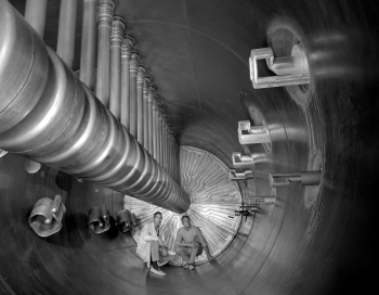 Super HILAC (Super Heavy Ion Linear Accelerator) was one of the first particle accelerators that could accelerate heavier elements to âatom-smashingâ speeds. The device was built in 1972 and played a significant role in four decades of scientific research at Lawrence Berkeley National Laboratory. In addition to being the launchpad for a variety of major experiments, the Super HILAC was crucial in the discovery of five superheavy elements.
In this photo, Lawrence Berkeley National Laboratoryâs Bob Stevenson and Frank Grobelch are sitting inside the Super HILACâs poststripper. The maze of piping behind them is meant to circulate cooling water through the accelerator. | Photo courtesy of Lawrence Berkeley National Laboratory. Super HILAC (Super Heavy Ion Linear Accelerator) was one of the first particle accelerators that could accelerate heavier elements to âatom-smashingâ speeds. The device was built in 1972 and played a significant role in four decades of scientific research at Lawrence Berkeley National Laboratory. In addition to being the launchpad for a variety of major experiments, the Super HILAC was crucial in the discovery of five superheavy elements.
In this photo, Lawrence Berkeley National Laboratoryâs Bob Stevenson and Frank Grobelch are sitting inside the Super HILACâs poststripper. The maze of piping behind them is meant to circulate cooling water through the accelerator. | Photo courtesy of Lawrence Berkeley National Laboratory.