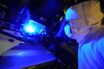 Solar Junction, in partnership with NREL, has developed solar cells that reach a record-breaking 44 percent efficiency -- meaning that more than 40 percent of the sunlight the solar cells are exposed to is converted into electrical energy. In this photo, an operator inspects a photolithography tool used to manufacture these solar cells. | Photo by Daniel Derkacs/SolarJunction. Solar Junction, in partnership with NREL, has developed solar cells that reach a record-breaking 44 percent efficiency -- meaning that more than 40 percent of the sunlight the solar cells are exposed to is converted into electrical energy. In this photo, an operator inspects a photolithography tool used to manufacture these solar cells. | Photo by Daniel Derkacs/SolarJunction.