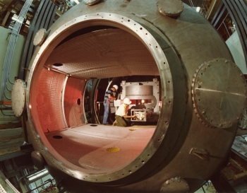 This 1978 photo shows two workers inside the Mirror Fusion Test Facility, a magnetic confinement fusion device designed and built at Lawrence Livermore National Laboratory. In this experiment, magnetic mirrors are placed at both ends of a central magnetic tube. Very hot and dense plasmas inside each mirror enhanced the confinement of another plasma inside the central tube, where the bulk of the fusion would occur. | Photo courtesy of Lawrence Livermore National Laboratory. This 1978 photo shows two workers inside the Mirror Fusion Test Facility, a magnetic confinement fusion device designed and built at Lawrence Livermore National Laboratory. In this experiment, magnetic mirrors are placed at both ends of a central magnetic tube. Very hot and dense plasmas inside each mirror enhanced the confinement of another plasma inside the central tube, where the bulk of the fusion would occur. | Photo courtesy of Lawrence Livermore National Laboratory.
