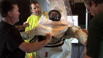 Trainers help a Plutonium Finishing Plant employee dress in the protective suit. Trainers help a Plutonium Finishing Plant employee dress in the protective suit.