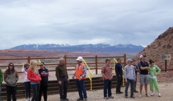 Students from the University of Utah contemplate the hillside geology at the rail load out area while Moab Federal Project Director Donald Metzler (in orange vest) addresses a question. The uranium mill tailings pile is behind and below the viewing area. Students from the University of Utah contemplate the hillside geology at the rail load out area while Moab Federal Project Director Donald Metzler (in orange vest) addresses a question. The uranium mill tailings pile is behind and below the viewing area.