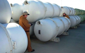 Workers inspect cylinders containing depleted uranium hexafluoride. Workers inspect cylinders containing depleted uranium hexafluoride.