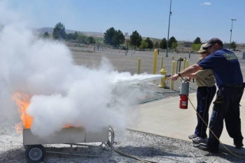 A Hanford site volunteer helps a Boy Scout practice the Pull, Aim, Squeeze, Sweep, or PASS, fire extinguishing technique at the Volpentest HAMMER Training & Education Center in Richland. A Hanford site volunteer helps a Boy Scout practice the Pull, Aim, Squeeze, Sweep, or PASS, fire extinguishing technique at the Volpentest HAMMER Training & Education Center in Richland.