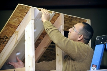 Daniel Tello demonstrates how to prepare an attic space for insulation using skills learned from the First Choice Program. | Photo courtesy of HCDC, Human Capital Development Corp., Inc. and Scott Anderson Daniel Tello demonstrates how to prepare an attic space for insulation using skills learned from the First Choice Program. | Photo courtesy of HCDC, Human Capital Development Corp., Inc. and Scott Anderson