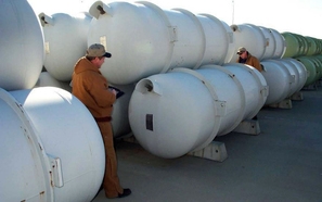 Workers inspect cylinders containing depleted uranium hexafluoride. Workers inspect cylinders containing depleted uranium hexafluoride.