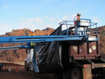 Laborers place a disposable liner in a tailings container. Laborers place a disposable liner in a tailings container.