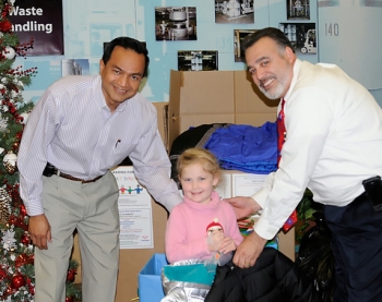 Aspen Cass, a relative of an EM Carlsbad Field Office (CBFO) employee, holds donated coats with Farok Sharif (left), president and project manager of Nuclear Waste Partnership, the WIPP management and operating contractor, and Joe Franco, manager of CBFO. Aspen Cass, a relative of an EM Carlsbad Field Office (CBFO) employee, holds donated coats with Farok Sharif (left), president and project manager of Nuclear Waste Partnership, the WIPP management and operating contractor, and Joe Franco, manager of CBFO.