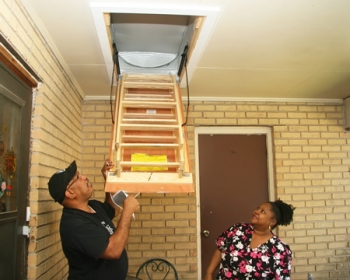 SMILE Weatherization Coordinator Venice Roberts shows client Shelia Sturgis an attic tent, which conserves energy and decreases costs. | Photo by Susannah Malbreau SMILE Weatherization Coordinator Venice Roberts shows client Shelia Sturgis an attic tent, which conserves energy and decreases costs. | Photo by Susannah Malbreau