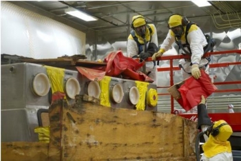 Workers process the first box of waste in the new facility. Workers process the first box of waste in the new facility.
