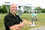 Michael Dunn, Deputy Director of Facilities Management at Argonne National Laboratory, setup a program that encouraged employees to cut their energy use during peak summer months and resulted in more than $475,000 in savings. Here he stands next to an electrical vehicle fueling station that charges cars with solar energy. | Image courtesy of Argonne National Laboratory.