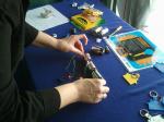 Volunteer Alison Mize demonstrates how to build an electrical circuit using a string of lights and battery at the Vehicle Technologies Program booth at the 2011 Solar Decathlon. | DOE photo, courtesy of April Saylor