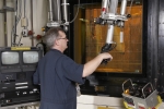 A Savannah River Remediation employee uses a manipulator located inside a shielded enclosure at the Defense Waste Processing Facility, where a melter pours molten glass into a canister.